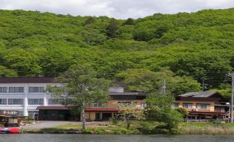 Lakeside buildings beneath a densely wooded hillside.