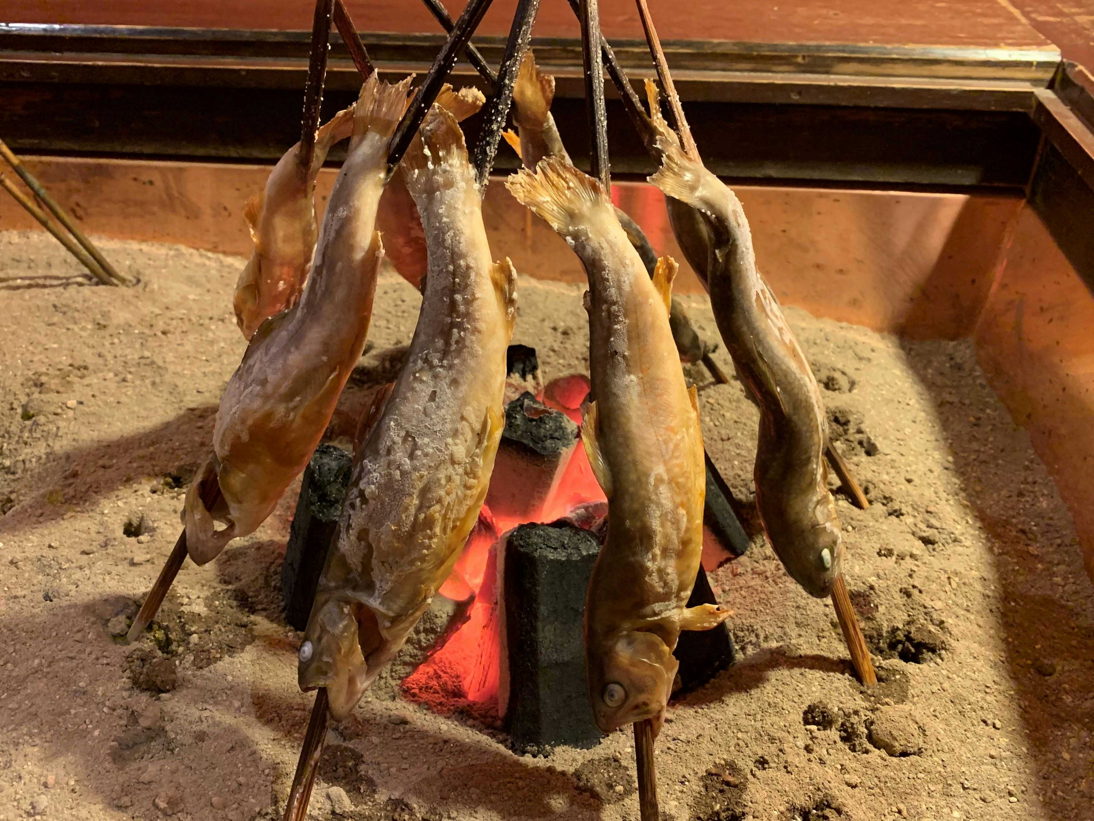 Ryokan Murayama with river fish roasting around glowing charcoal in a sunken hearth.