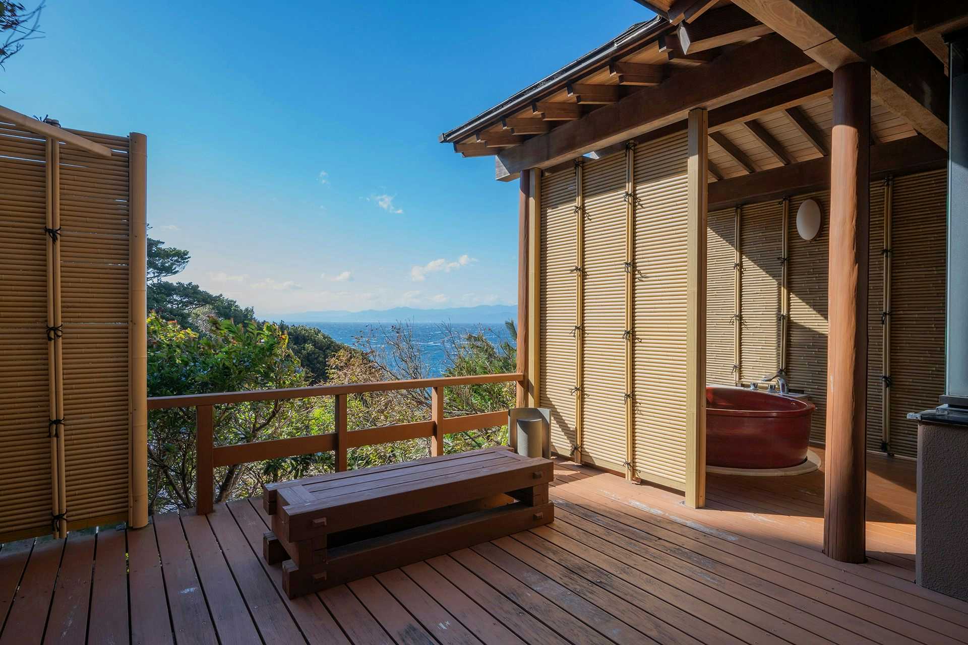 Nishi-Izu Dining Nishi-Izu Koyoi with a timber terrace facing the sea and forested coastline.