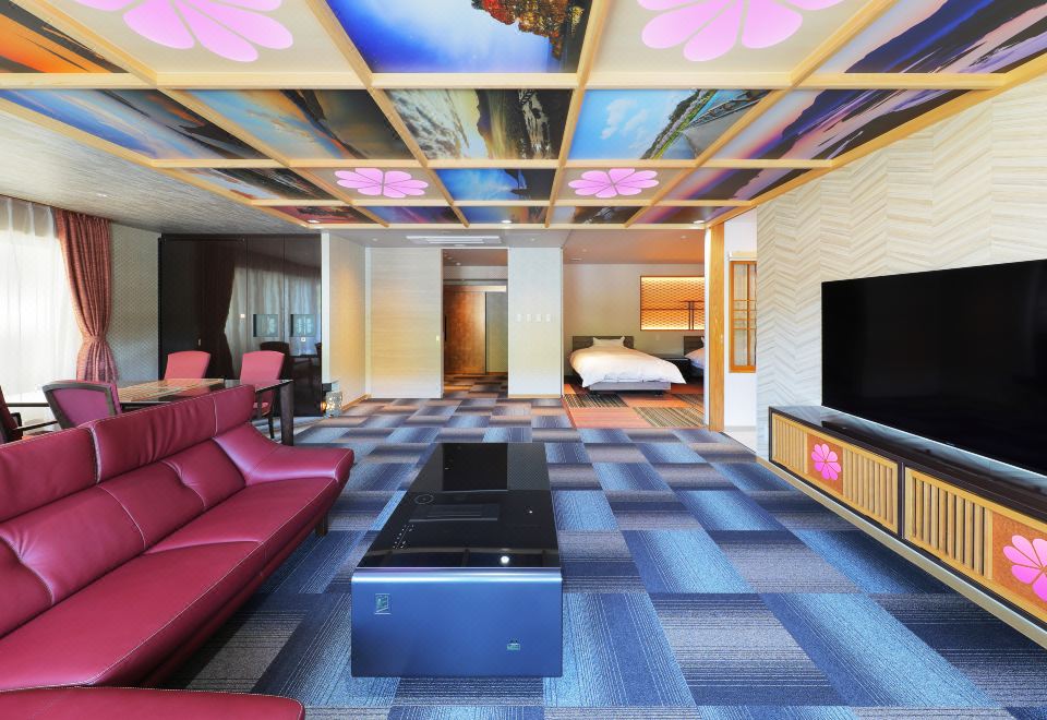A suite sitting area with red sofas and a built-in wooden bath.