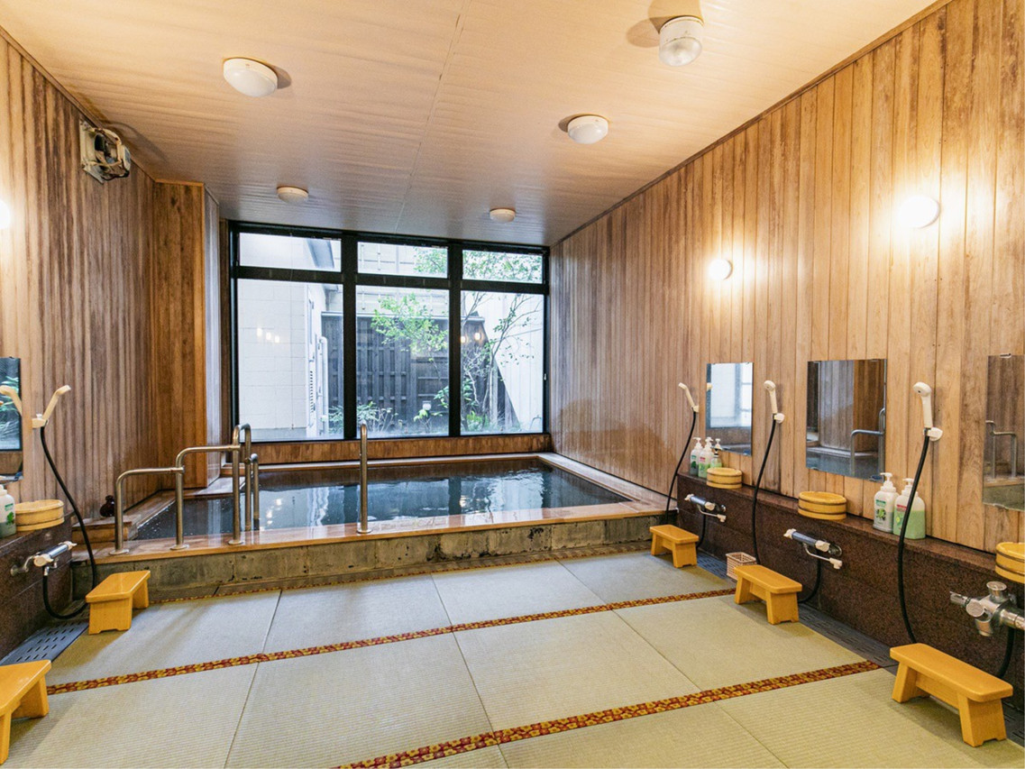 A wood-paneled bath is lit by windows overlooking greenery.