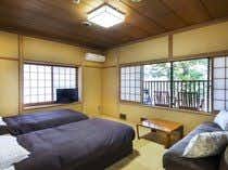 A compact guest room with dark bedding and tatami flooring.