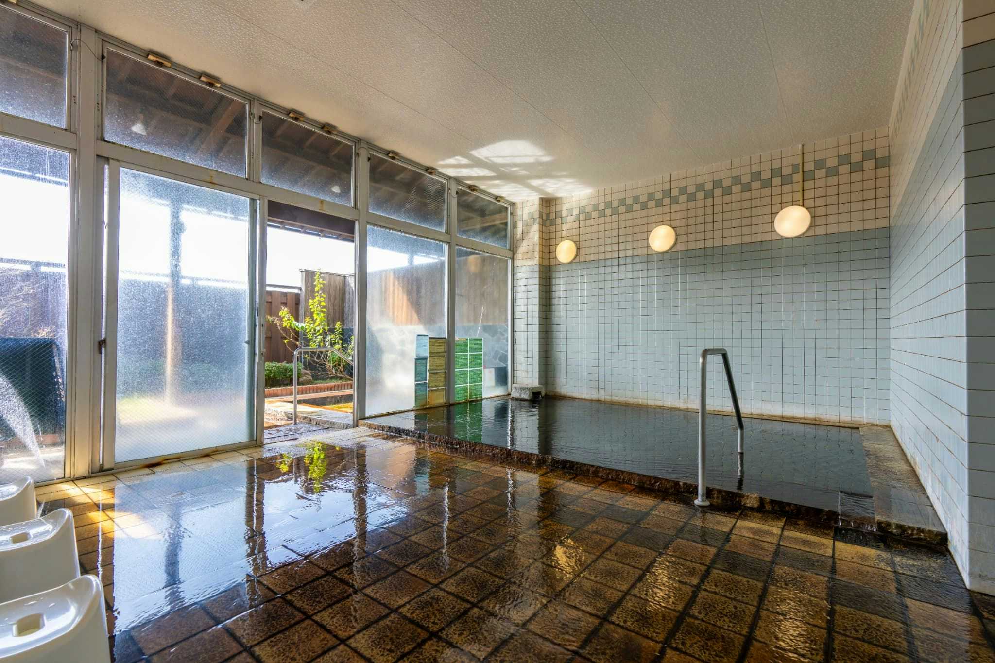 Harazuru Onsen Enmeikan with a bright indoor tiled bath lined with broad windows.