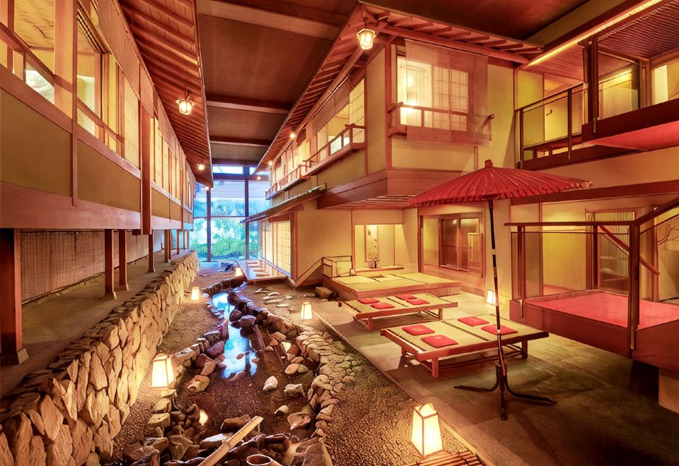 An indoor courtyard with a stream and red parasol.