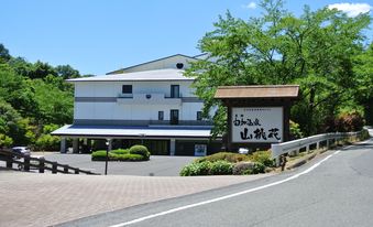 White hotel exterior beside a curving road and a large Japanese sign.