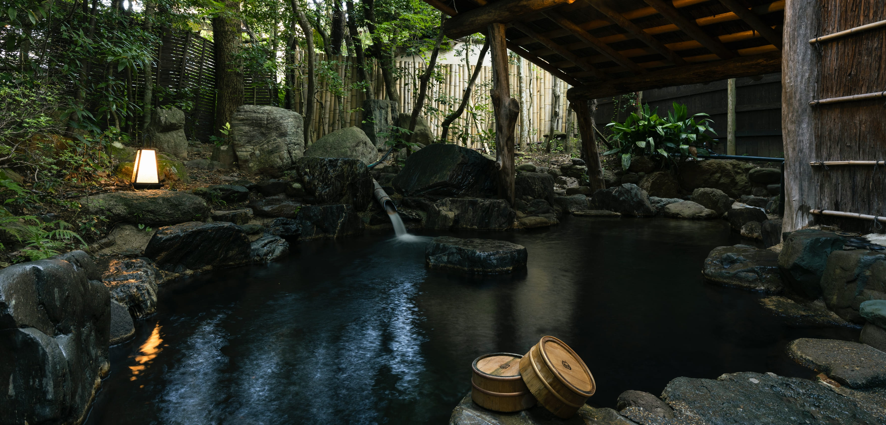 Rock-lined outdoor bathing pool among trees.