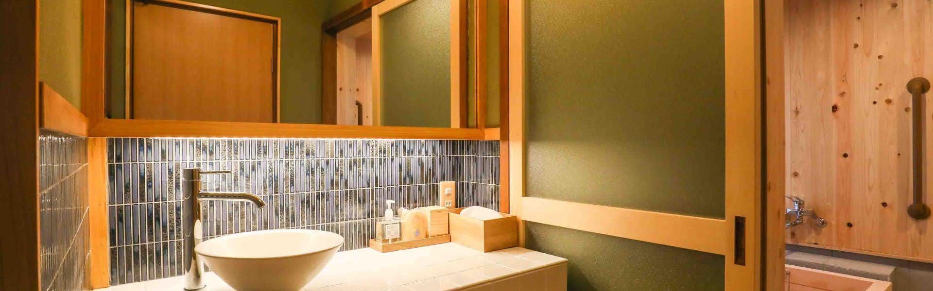 Senzairo Orange vanity with round white basin, wall mirror, pale walls, and wood trim.