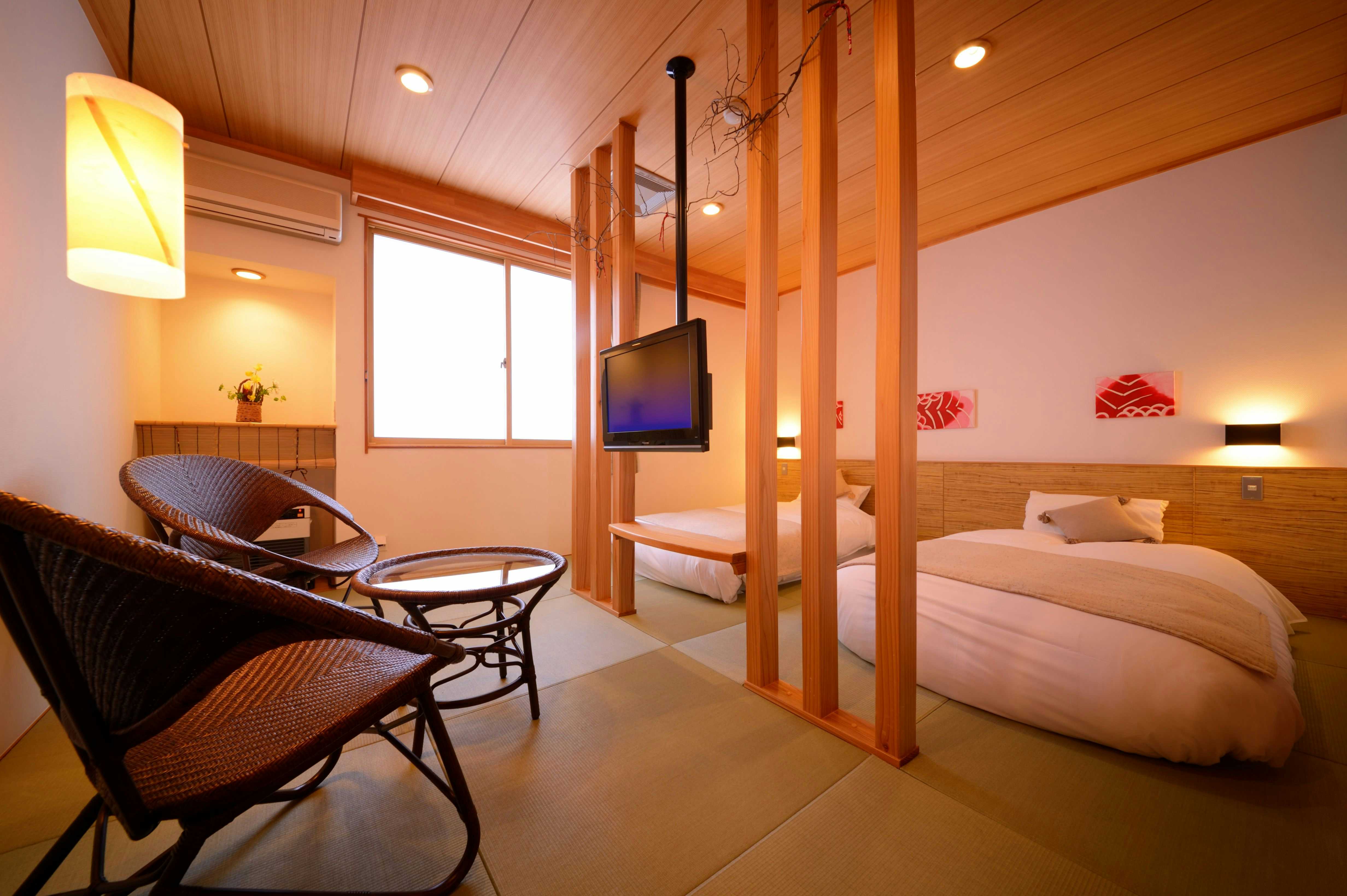Ajigasawa Onsen Suigun no Yado with a warm room with twin beds behind a wicker lounge chair.