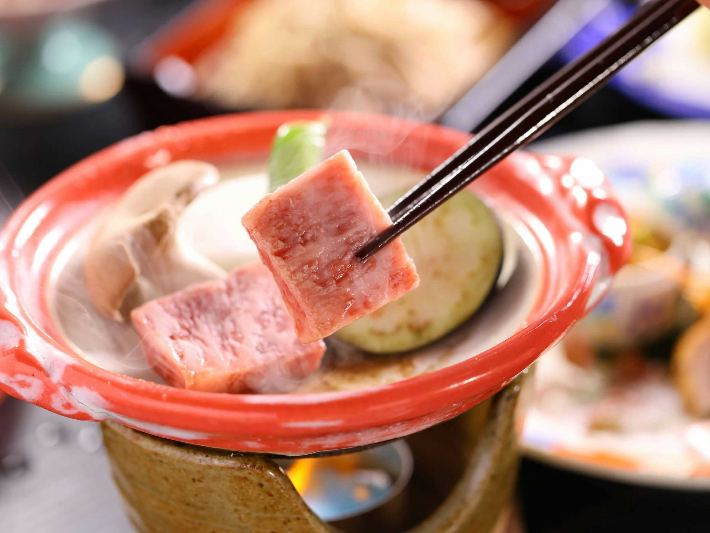 Onsen Ryokan Yama no Takohei with a seared cube of marbled beef lifted from a red dish.