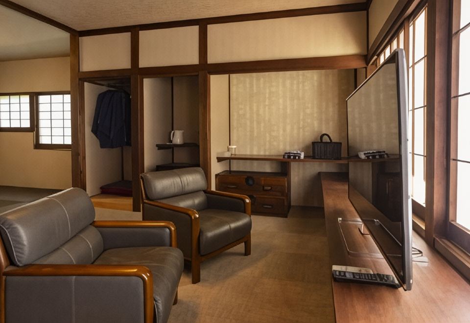 Armchairs and a television in a warm wood-framed guest room.