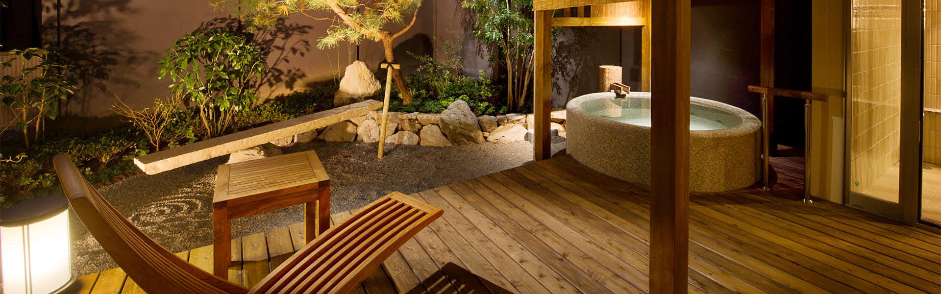 Migiwaya terrace with chairs and a round stone bath beside a garden