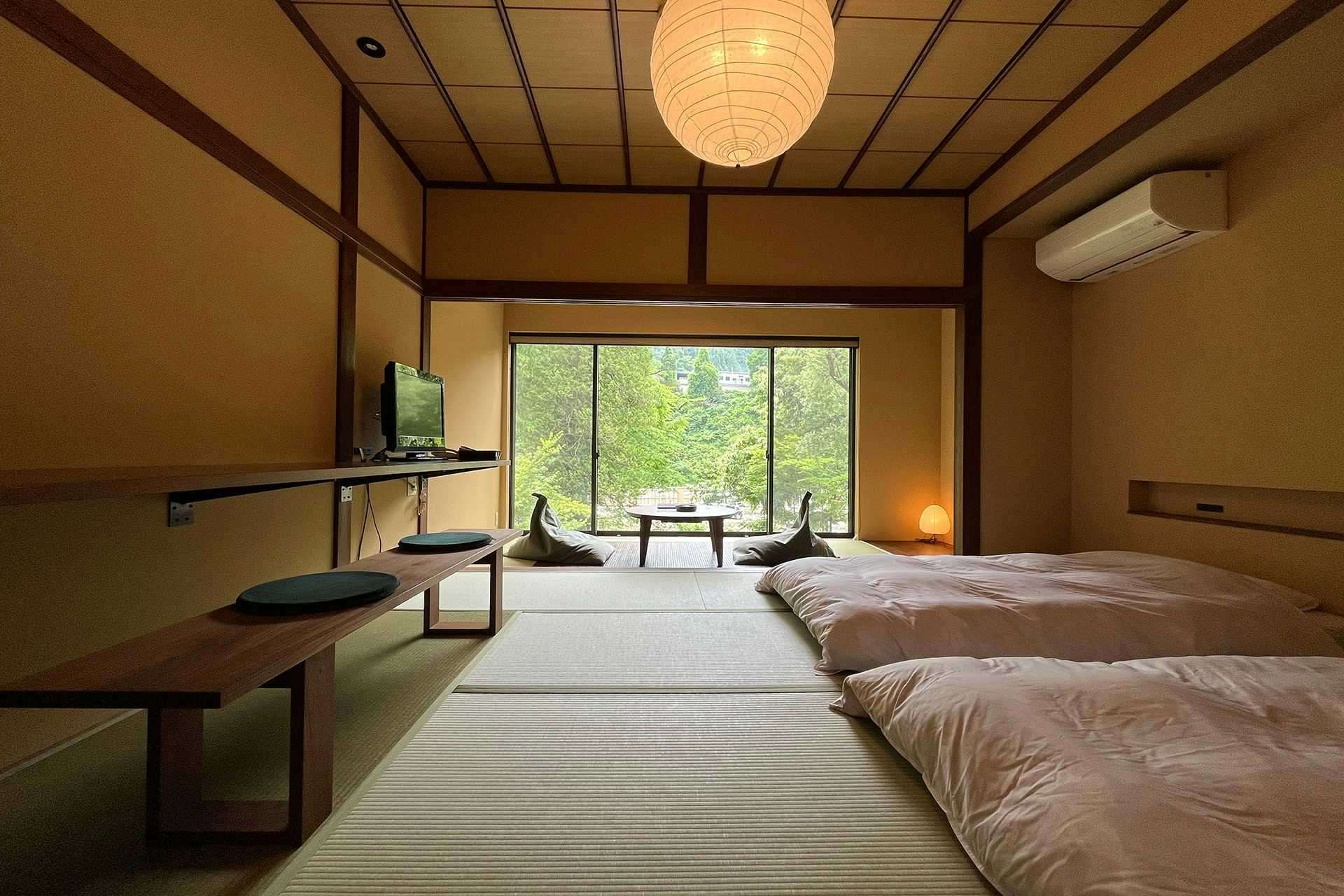 Echigo Tanaka Onsen Shinano-so with a tatami bedroom with futons facing leafy windows.
