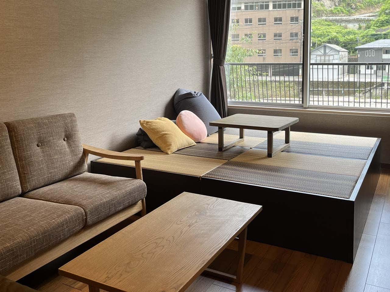 ryokan tenryu with a modern guest room with a sofa, low table, and raised tatami area.