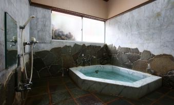 A compact bath with stone wall facing and handheld showers.
