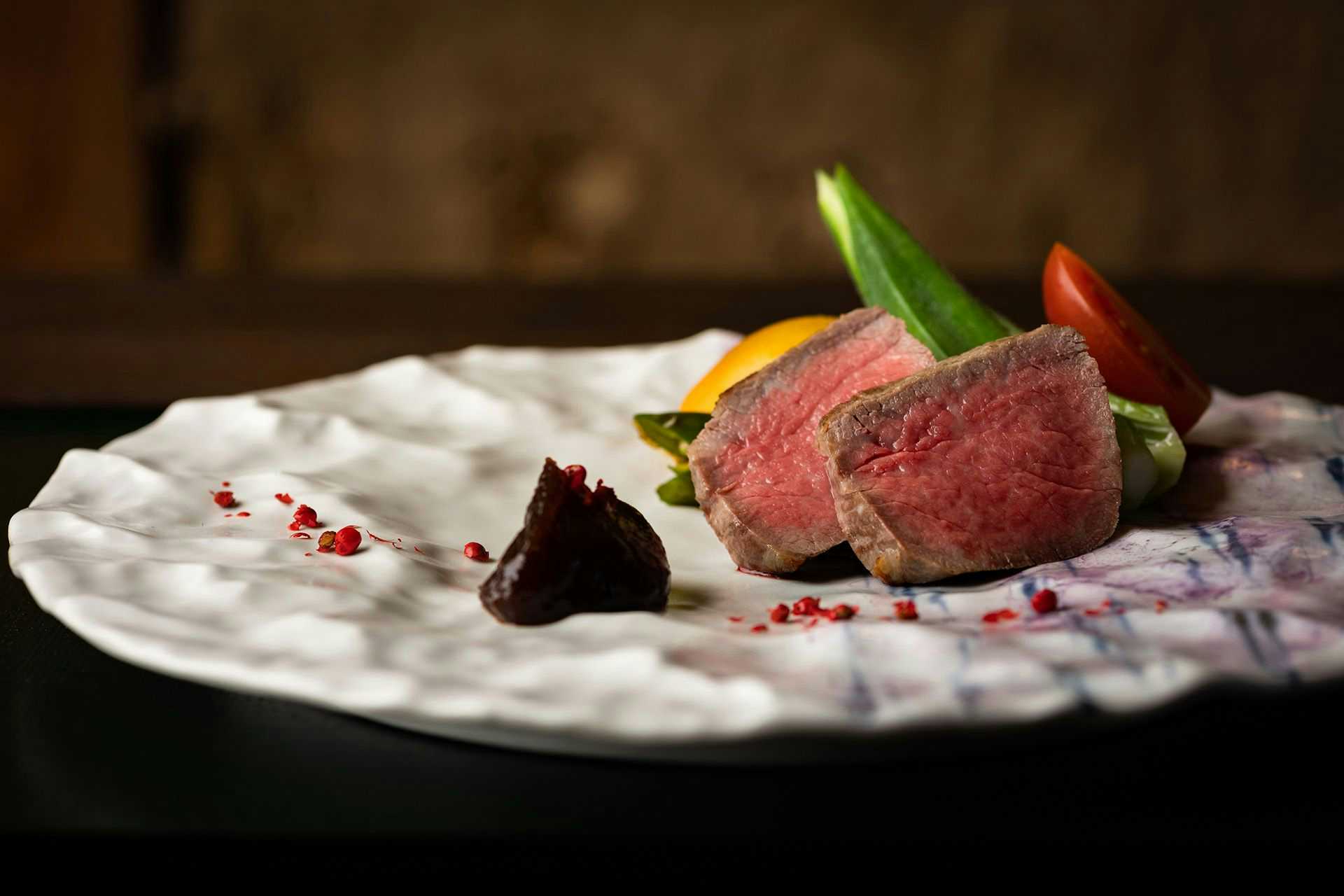 Kinosaki Onsen Tsuchiya Ryokan with slices of roasted beef presented on a white ceramic plate.