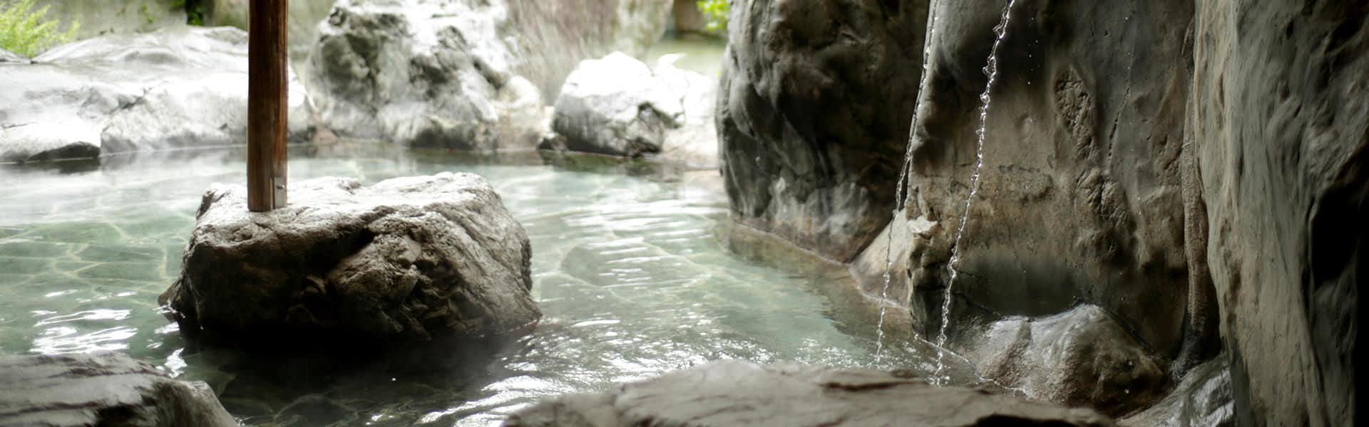 Yurui no Yado Esan with an outdoor rock bath surrounded by flowing water.