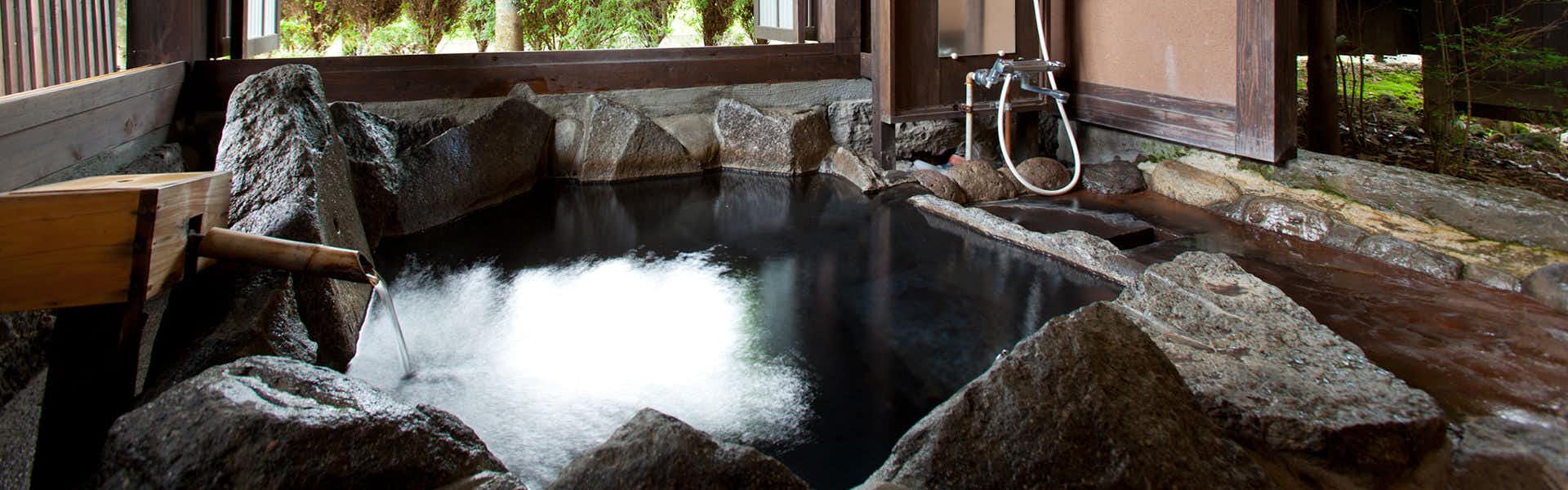 Shugetsu with a private rock bath surrounded by timber and garden foliage.