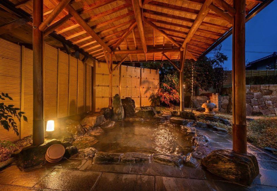 A roofed outdoor bath glows in the evening light.