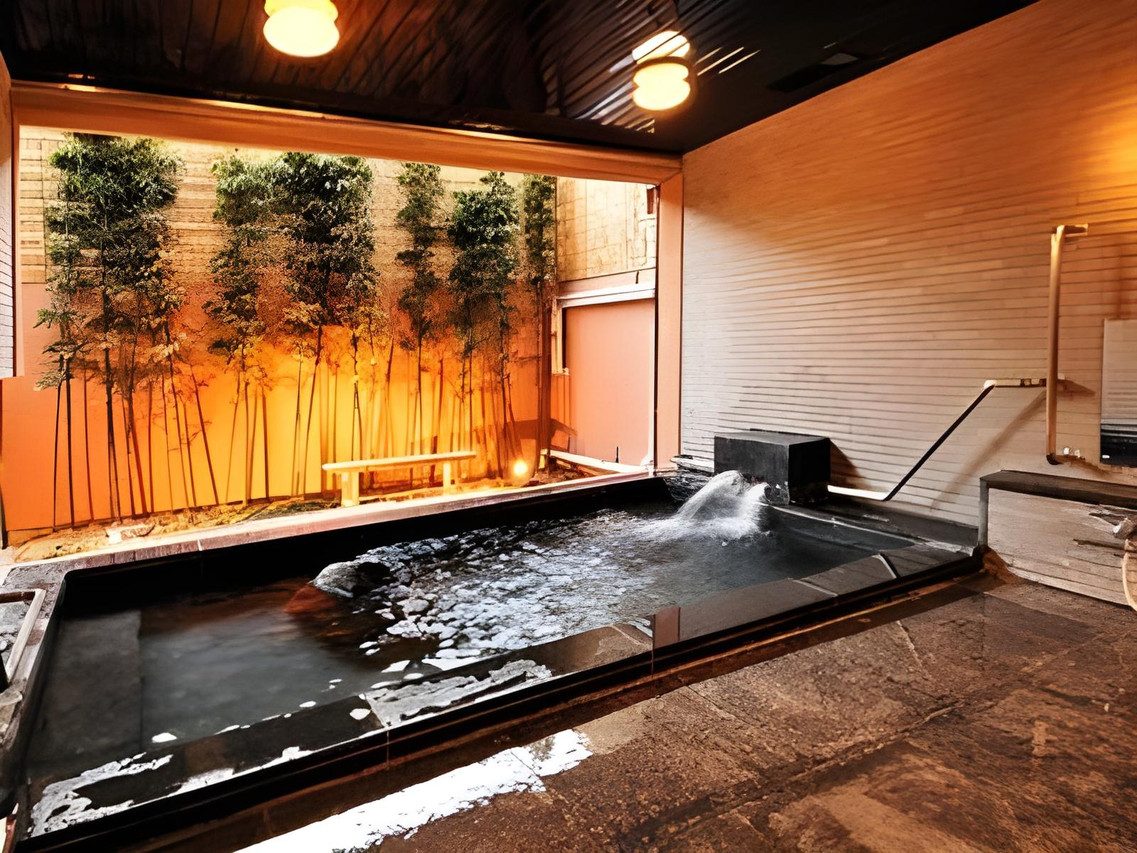 A rectangular bath beside warmly lit bamboo screening.