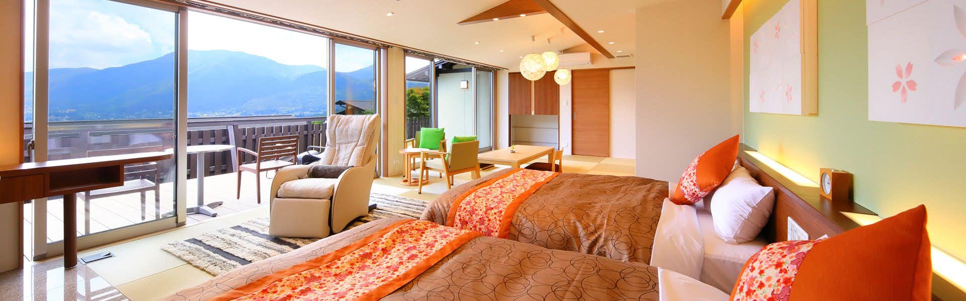 Yufuin Hanayoshi with a View of the Morning Mist with a bright suite with orange bedding and mountain balcony.