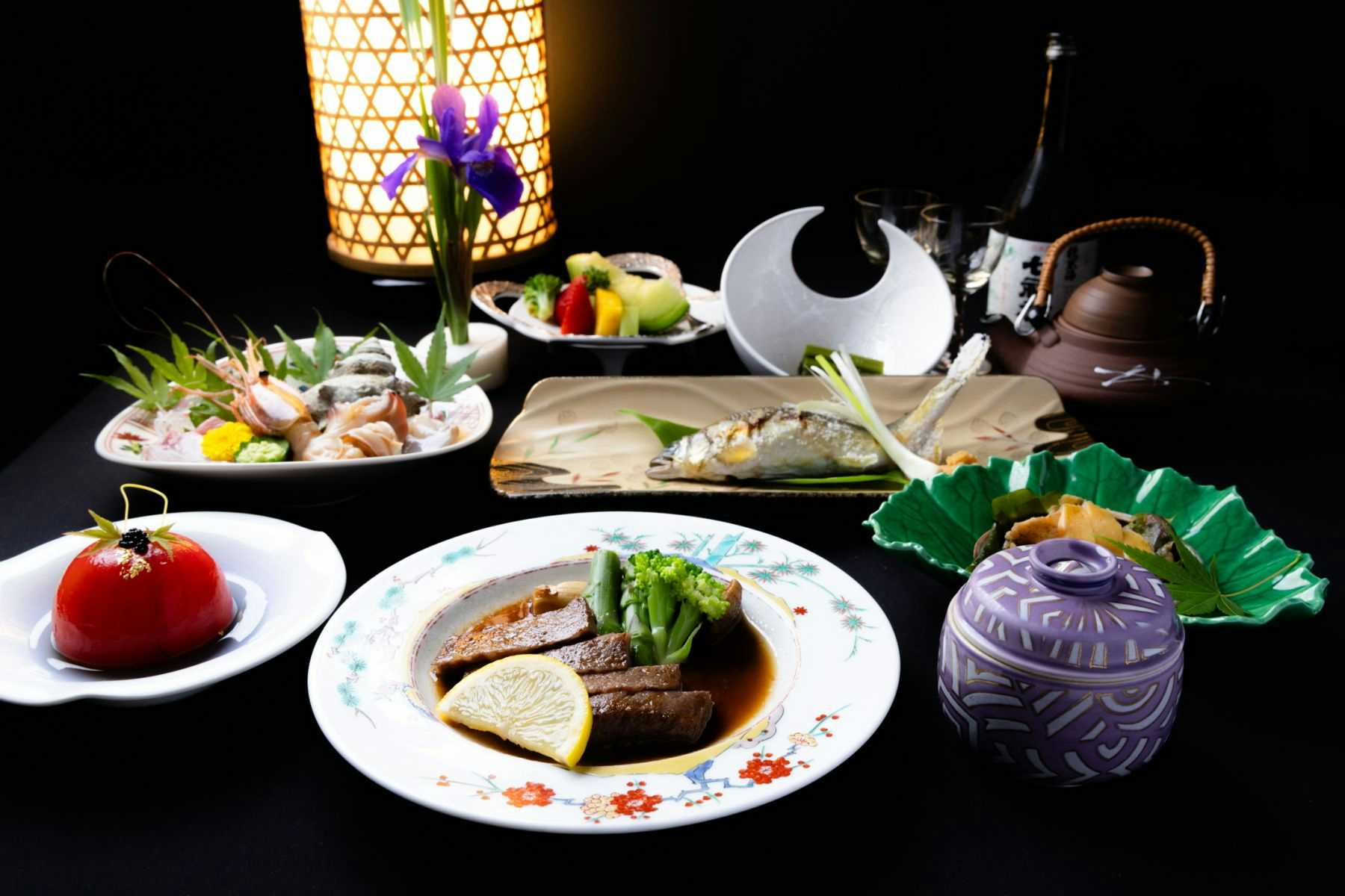 Kappo Ryokan Hiromitei with this scene, where its plated dinner gathers colorful small dishes around a central covered bowl.