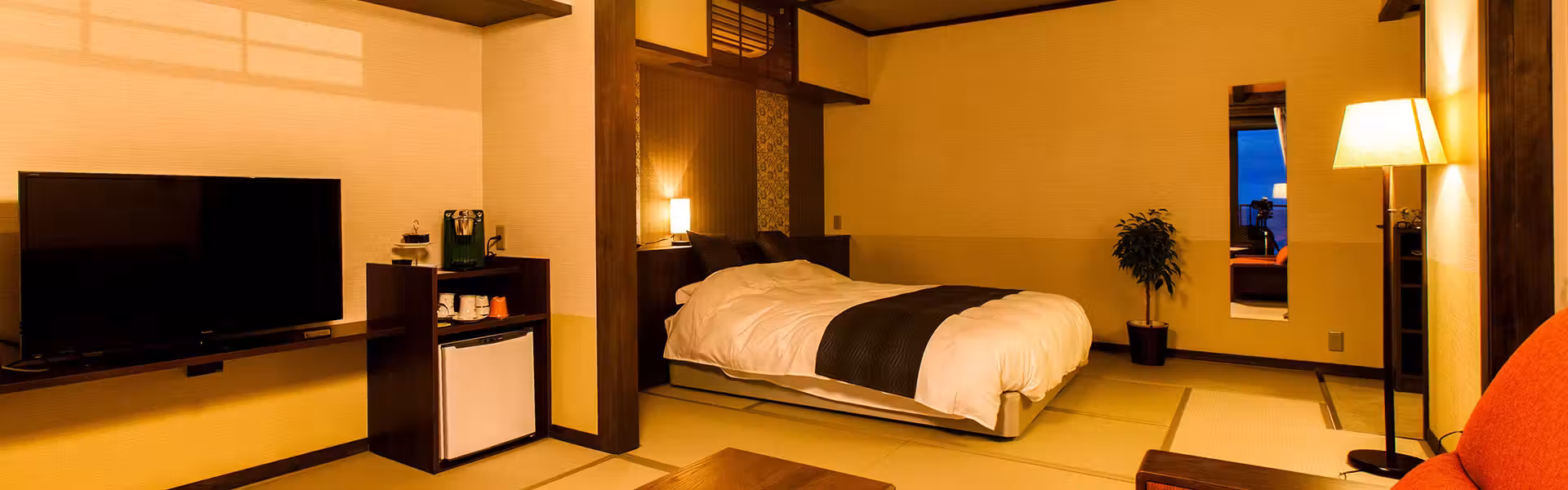 Yusai Resort Hibiki with this scene, where a spacious guest room pairs western beds and lounge seating with sea views.