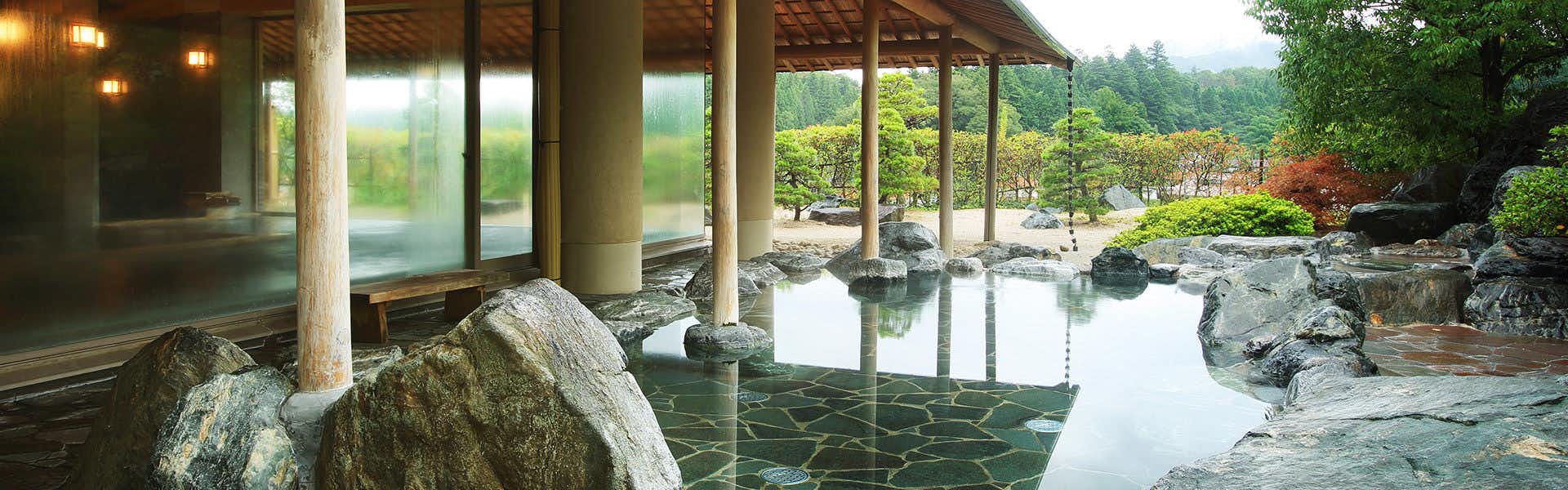 Kamedake Onsen Tamamine Sanso with an outdoor rock bath surrounded by a clipped garden.