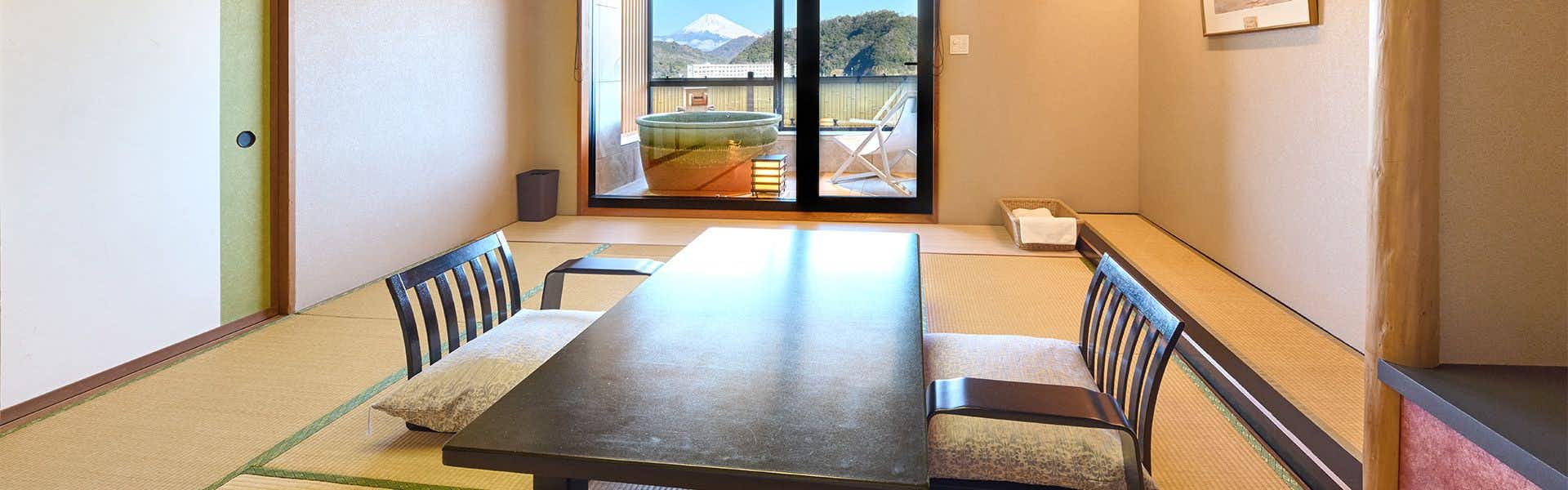 Fugaku Hanabusa Wooden-floored dining room with dark table, striped-pattern chairs, white place settings, and mountains framed by windows.