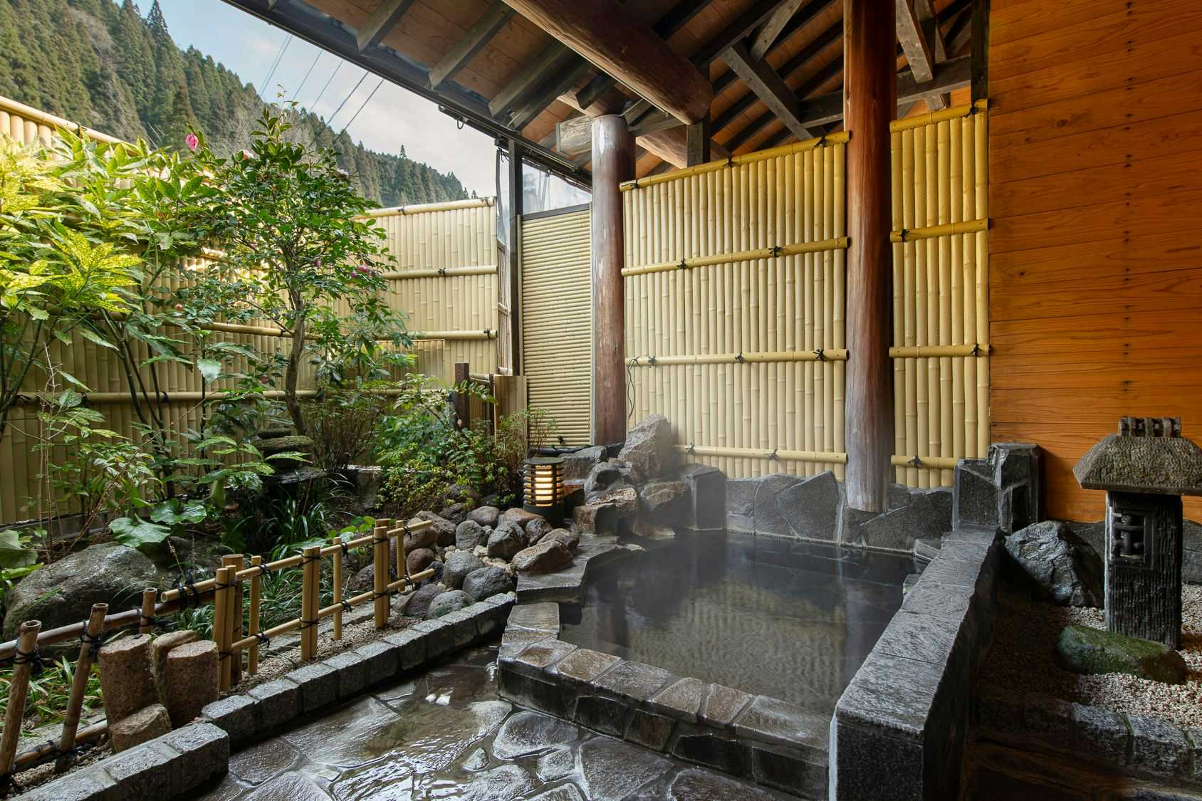 Sanso Matsuya an open-air stone bath enclosed by a bamboo screen and garden.