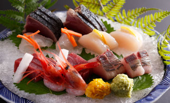 Assorted sashimi with shrimp, tuna, scallops, seaweed, and garnishes.