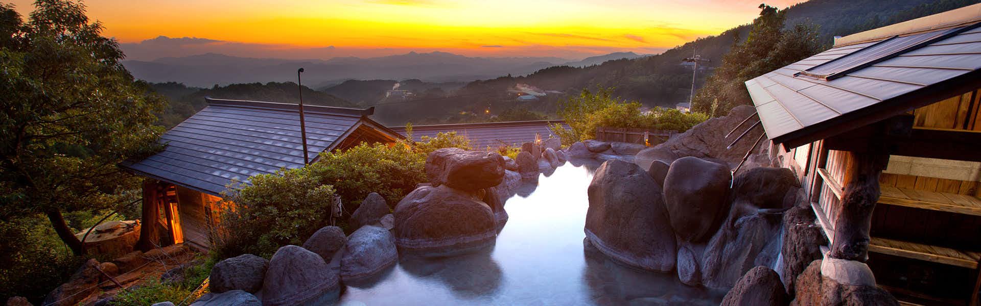 Ryokan Sansui with an outdoor rock bath overlooking an orange sunset.