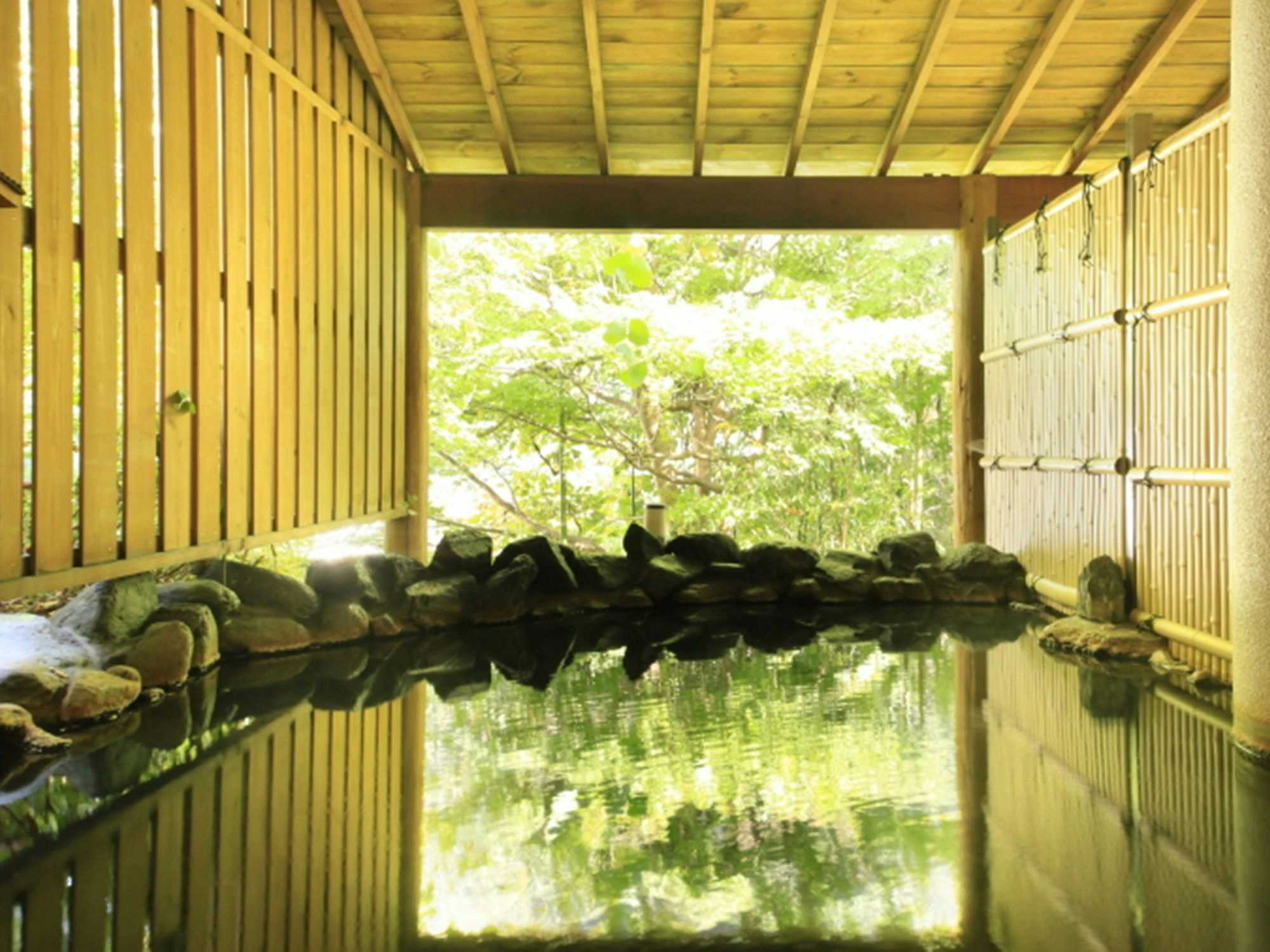 Genbi no Yado Aizuya with an open-air stone bath enclosed by pale bamboo screens.