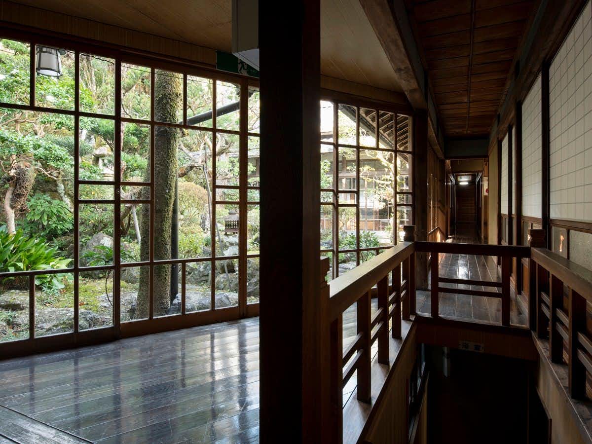 Ryori Ryokan Asahikan with a timber corridor lined with windows onto garden greenery.