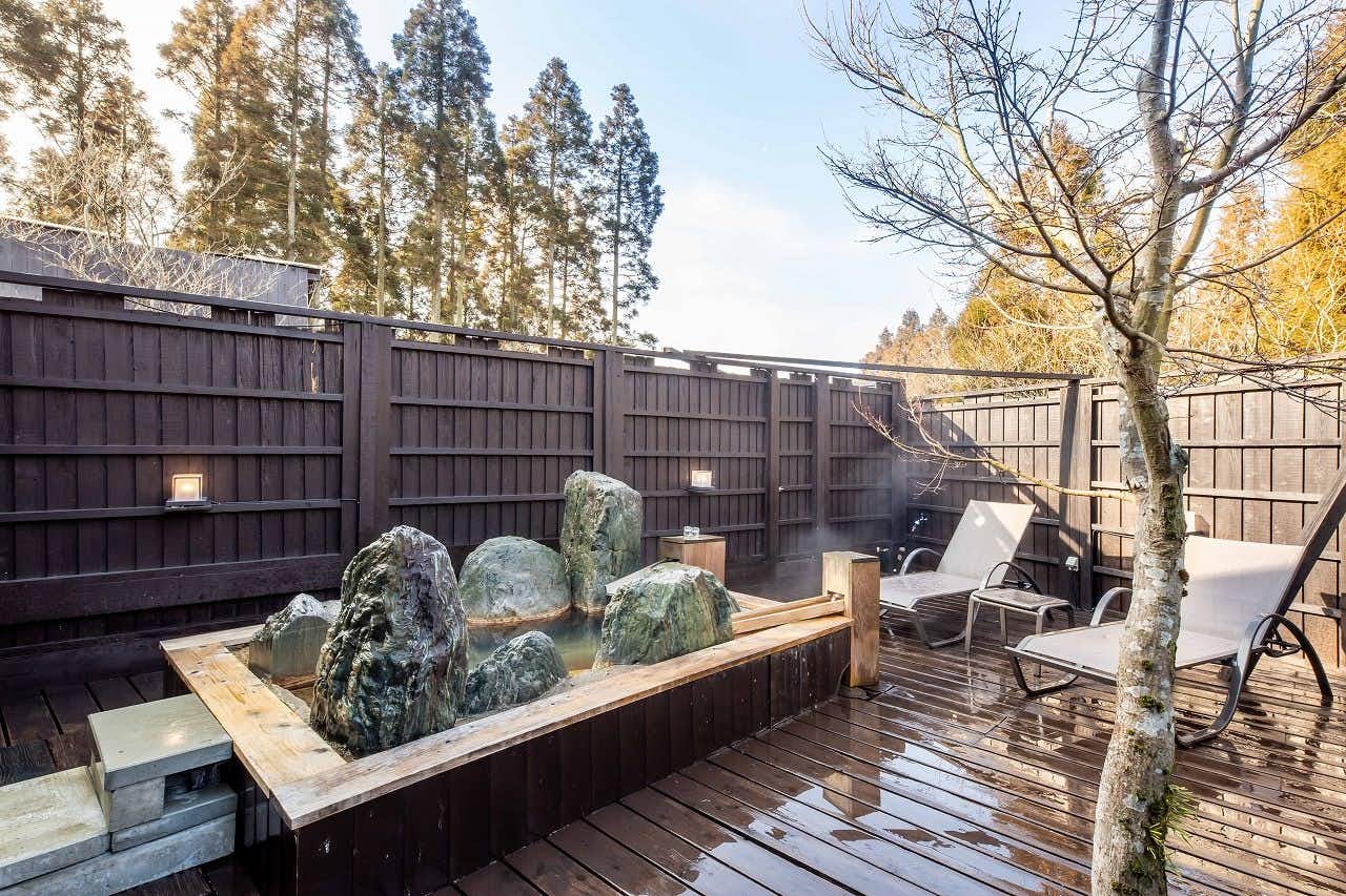 Hanare no Yado Hanagokoro with an open-air bath enclosed by dark fencing and standing stones.