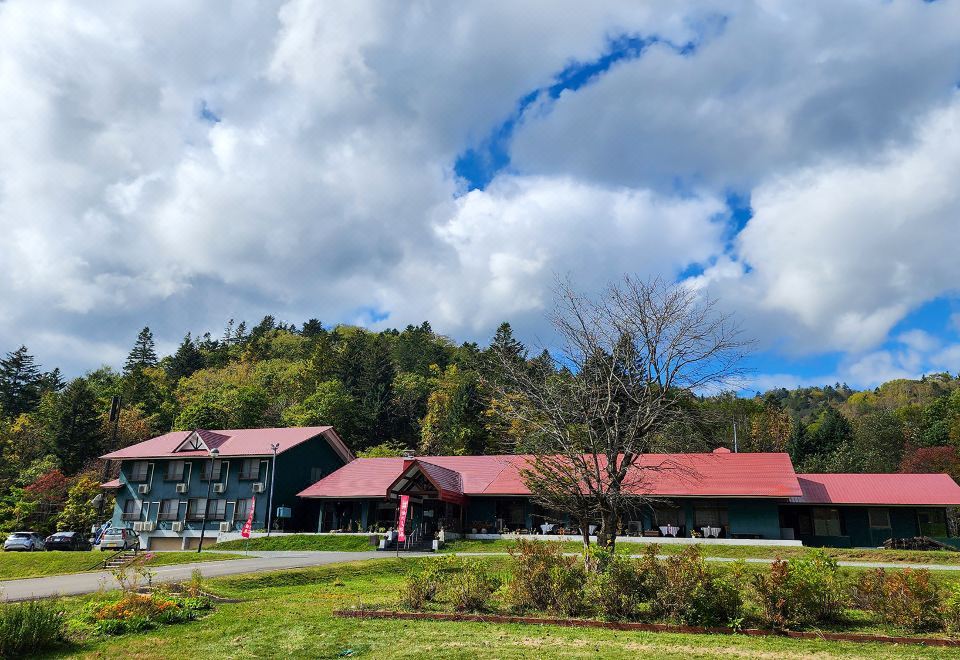 The red-roofed property beneath wooded hills.