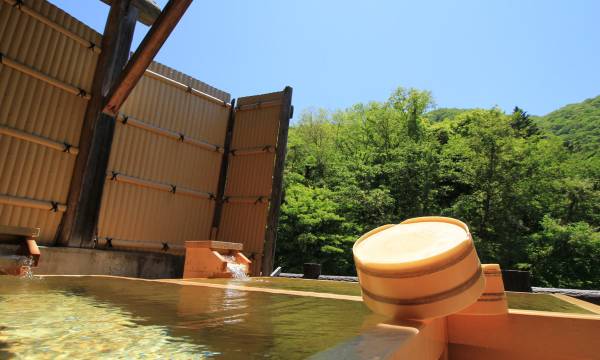 An outdoor bath with a wooden wash bucket.