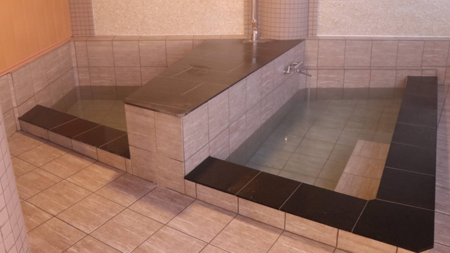 Two small rectangular baths set into a tiled bathing room.