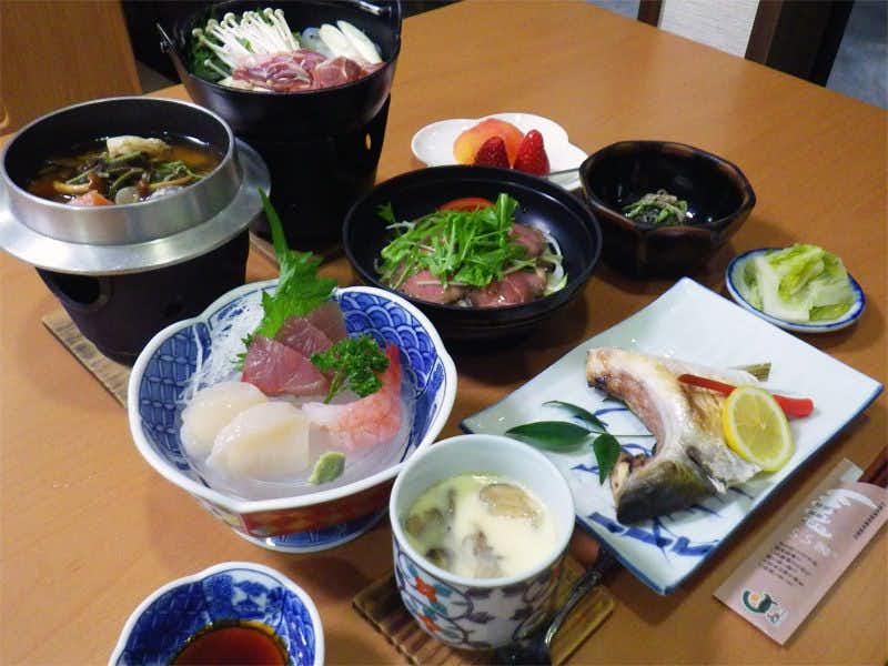 Oishiya Ryokan with a Japanese dinner arranged around sashimi, rice, and grilled fish.