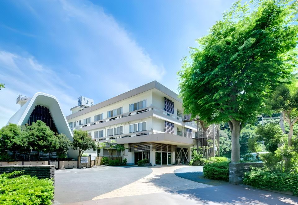 A light-colored resort building is framed by a leafy tree.