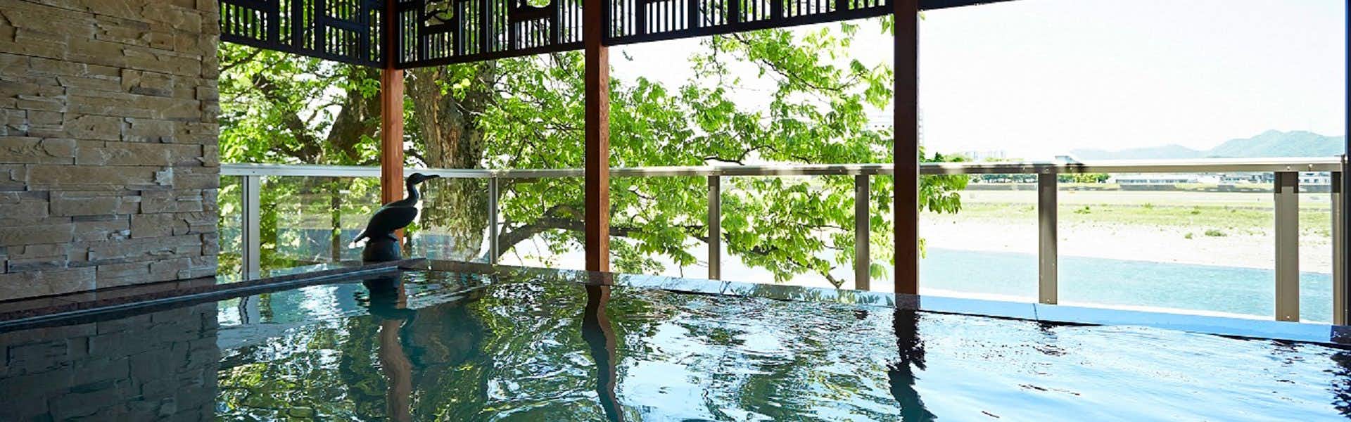 Juhachiro with a broad indoor bath overlooking the river through tall windows.