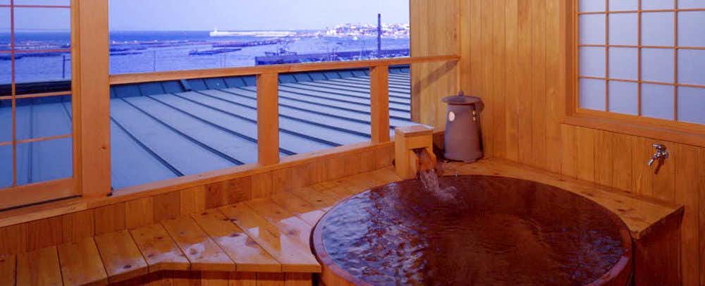 Ajiro Kanko Hotel with a private round timber bath overlooking the blue sea.