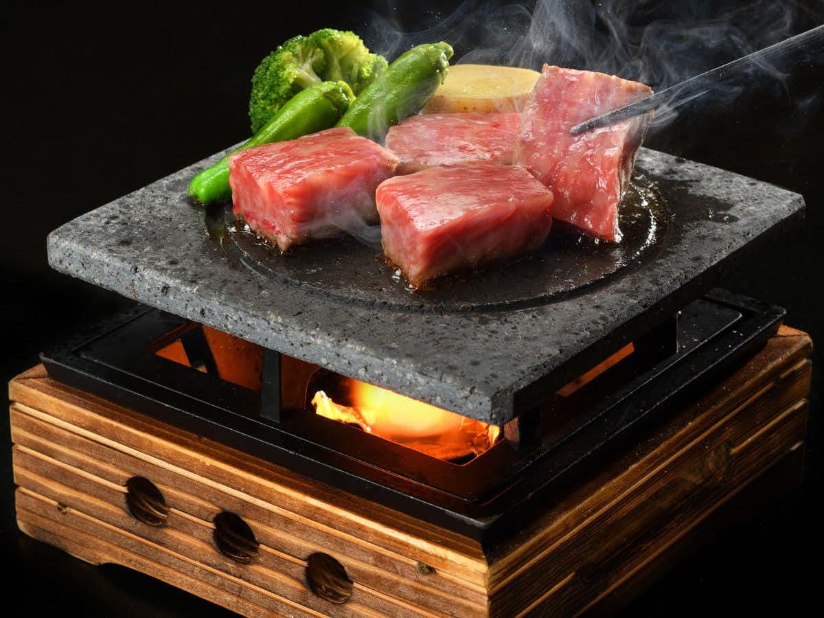 Iizaka Onsen Surikamitei Ootori with thin slices of beef cooking on a round tabletop grill.