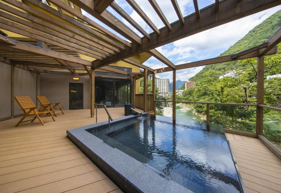 A rectangular open-air bath under a slatted pergola beside trees.