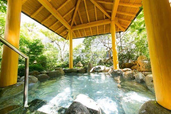 Mutsumi Inn with a bright stone bath beneath a yellow timber pavilion.