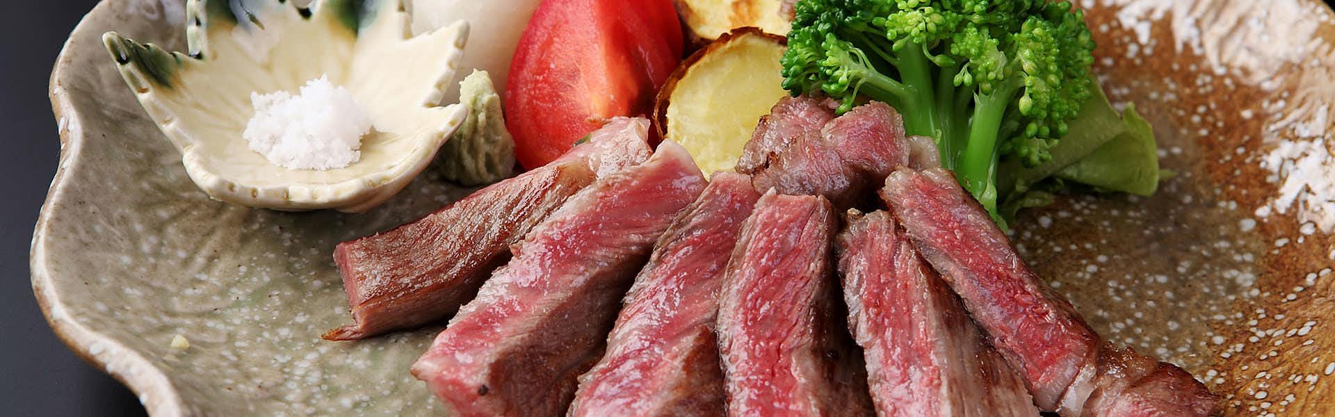 Tsukasaya Ryokan with sliced steak presented on a textured ceramic plate.