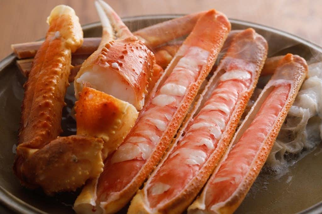 Kinosaki Onsen Tsuruyaryokan with large cooked crab legs arranged across a metal tray.