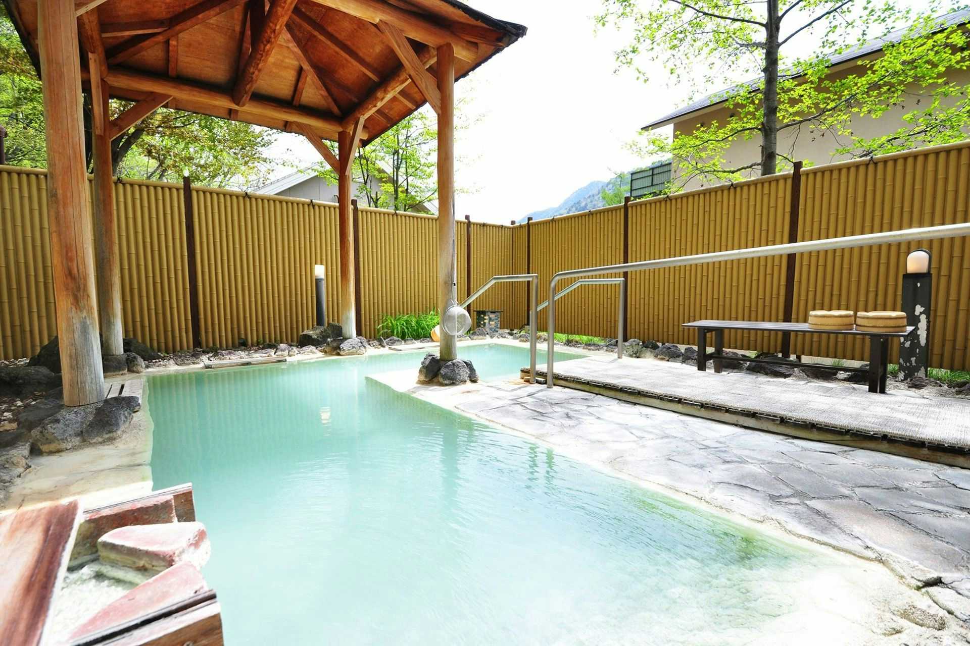 Yumoto Itaya with a milky blue open-air bath beneath a timber canopy.