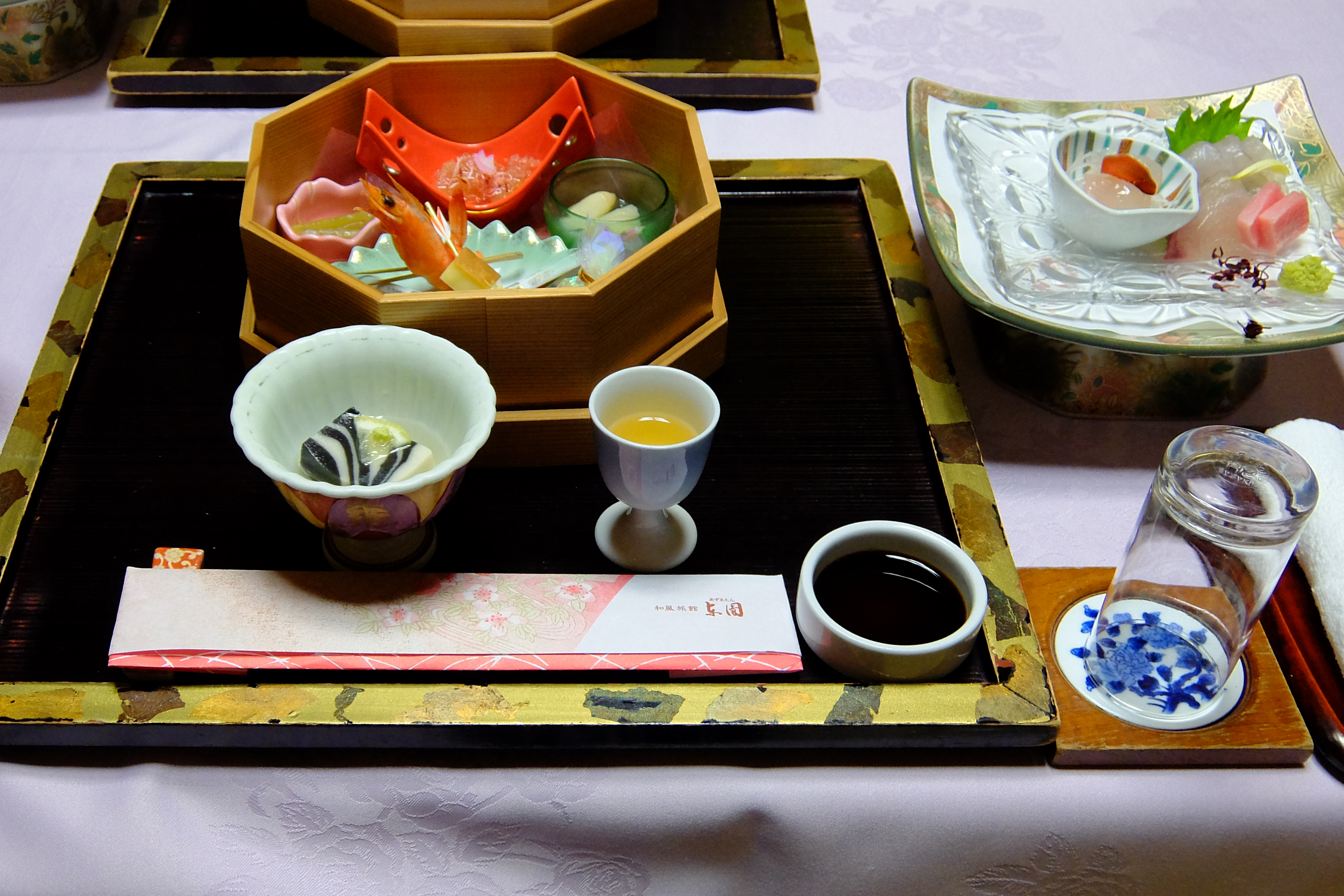 Unzen Onsen Gensen Kakenagashi & Oshidori no Ike wo Nozomu Bishoku no Yado Azumaen with small-dishes, whole-shrimp, sliced-fish and cups arranged-across lacquer-trays.