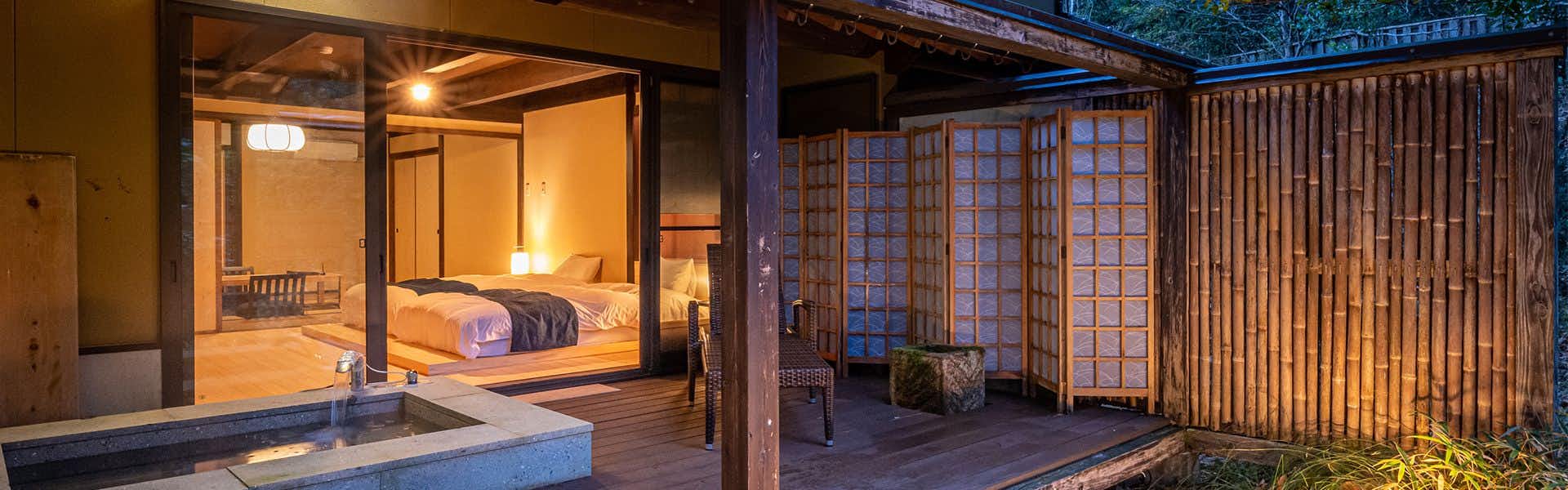 Ryokan Nushiya Wooden raised platform with bedding, latticed window screens, white fabric draping, exposed wooden beam structure