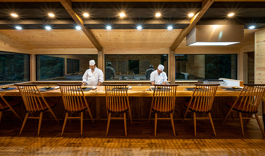 Wooden dining room with chefs working behind the counter.